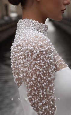 a woman with pearls on her neck wearing a white dress