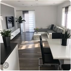 a living room filled with furniture next to a white table and black leather chairs in front of a flat screen tv