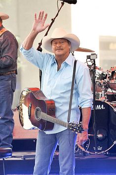 a man with a guitar waves to the crowd