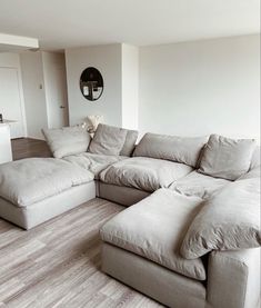 a large sectional couch sitting on top of a hard wood floor in a living room