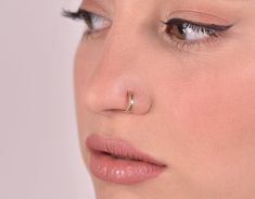 a close up of a woman with a nose ring on her nose and piercing in the middle