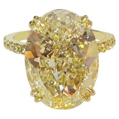 a fancy yellow diamond ring with two rows of diamonds on the band and an oval center stone