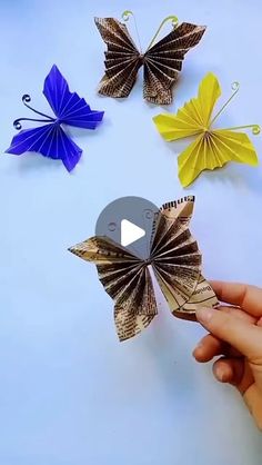 someone is holding an origami butterfly in front of several other butterflies on the table