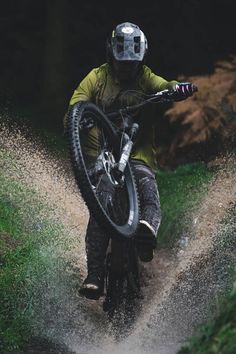 a man riding a bike down a dirt road next to grass and trees in the background