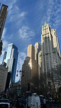 there are many tall buildings in the city with blue sky and clouds above them,