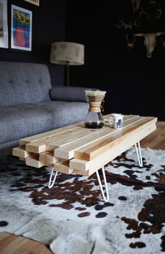 a wooden table sitting on top of a rug in front of a couch and coffee table