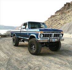 a blue truck parked on top of a dirt road