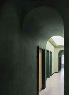 an empty hallway with green walls and doors