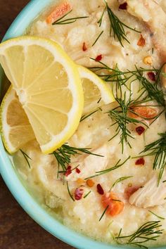 a blue bowl filled with mashed potatoes topped with lemon wedges and garnished with fresh herbs