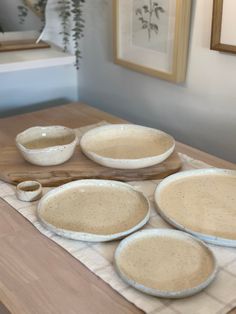 four bowls and three spoons on a wooden table in front of a framed painting