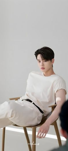 a young man sitting on top of a wooden chair