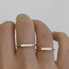 a woman's hand wearing a gold ring with two thin bars on the band