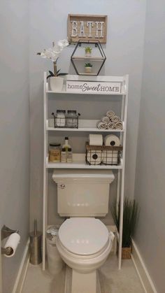 a white toilet sitting in a bathroom next to a shelf with items on top of it