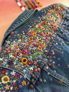 a pair of blue jean shorts with colorful flowers on them and crayons in the background