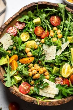 a salad with tomatoes, avocado and chickpeas in a wooden bowl