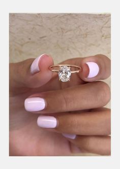 a woman's hand with pink and white manicured nails holding a diamond ring