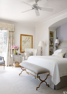 a bedroom with a white bed and ceiling fan