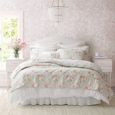 a bedroom with pink and white wallpaper, floral bedding, and a chandelier