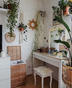 a room with a desk, mirror and plants on the wall