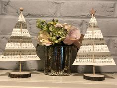 three wooden christmas trees sitting on top of a white table next to sheet music sheets