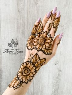 a woman's hand with henna tattoos on it and flowers painted on the palm