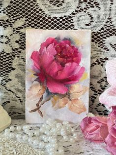 a pink flower sitting on top of a table next to pearls