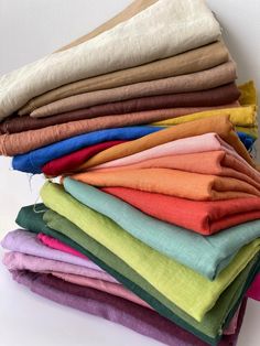 a stack of different colored linens sitting on top of each other in front of a white wall