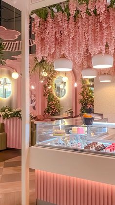 the interior of a pastry shop with pink flowers hanging from the ceiling and decorations on the walls