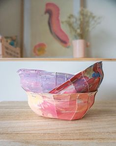 two bowls sitting on top of a wooden table next to a vase with flowers in it