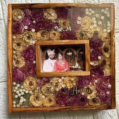 a wooden frame with flowers on it and a couple's photo in the center