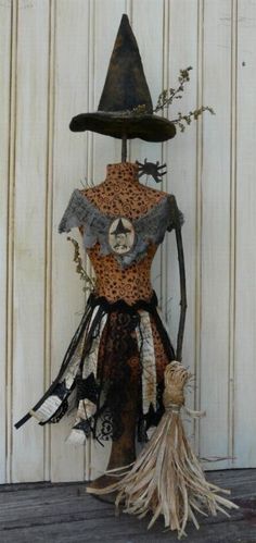 a scarecrow with a black hat on it's head is standing next to a white wall