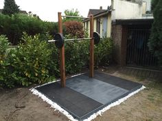 an outdoor gym in front of a house with trees and bushes behind it, on the ground