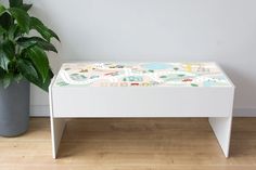 a white bench sitting next to a potted plant on top of a hard wood floor