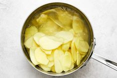 a pot filled with sliced apples sitting on top of a white counter next to a spoon