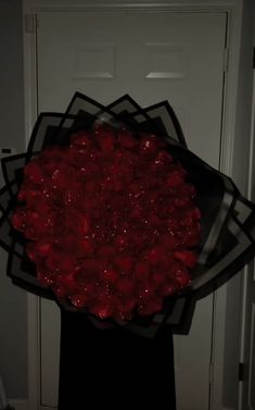 a person standing in front of a white door holding a black plate with red food on it