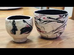 two black and white vases sitting on top of a wooden table next to each other