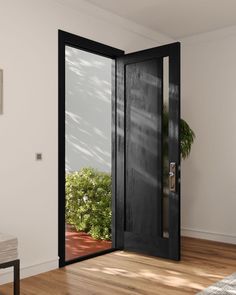 an open black door in a white room with wood flooring and potted plant