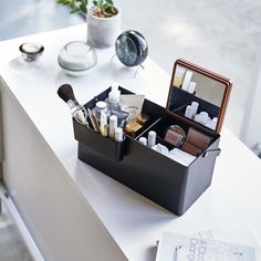 an open black box with makeup and other items in it sitting on a counter top