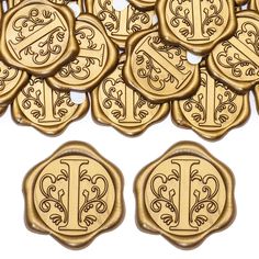 gold wax seal stamps with monograms and scrolls on the front, set against a white background