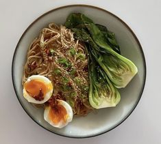 a bowl filled with noodles, vegetables and hard boiled eggs