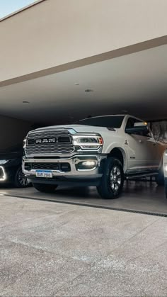 two pickup trucks parked in front of a garage with their lights on and the door open