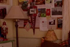 a lamp is sitting on a table in front of a wall covered with pictures and papers