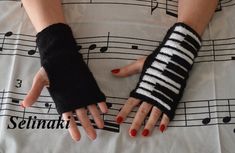 woman's hands with black and white knitted wrist warmers on top of sheet music notes