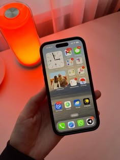 a person holding an iphone in front of a table with orange cups and utensils