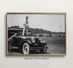 an old black and white photo of a man standing on top of a vintage car