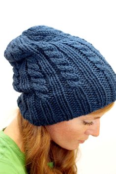 a woman wearing a blue knitted hat with braids on the top and side