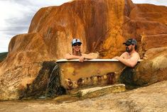 two people are sitting in an old bathtub on the side of a rock formation