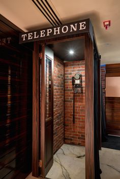 an open door leading to a phone booth with brick walls and doors that say telephone