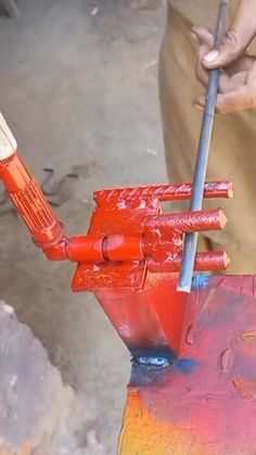 a man is working on an orange object with a paintbrush in his left hand