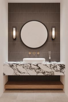 a bathroom with a marble counter top and round mirror above the sink, along with two wall sconces